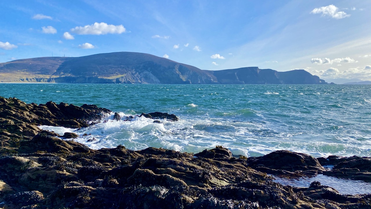 Atlantic waves breaking on rocks with Achill cliffs beyond