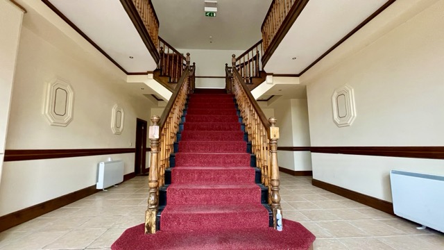 Restored building entrance hall with timber staircase