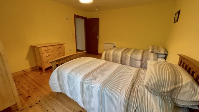 Twin bedroom with wooden floor and warm lighting