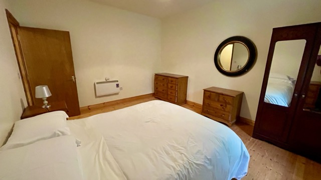 Double bedroom with wooden furniture and round mirror