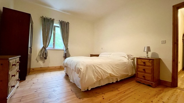 Double bedroom with wooden floor and window curtains