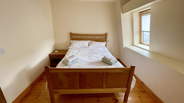 Bright double bedroom with wooden bed and deep window