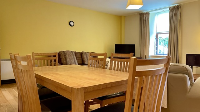 Dining table and living area with warm yellow wall