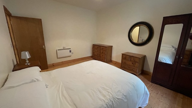 Double bedroom with dressers and round mirror