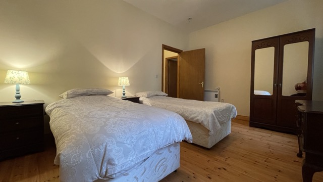 Twin bedroom with bedside lamps and wooden wardrobes
