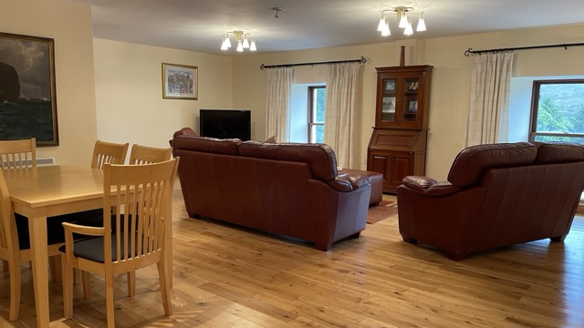 Open-plan living space with red leather sofas and dining area