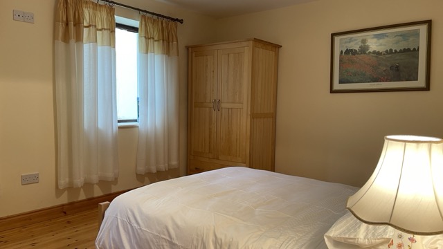 Double bedroom with wardrobe, curtains and bedside lamp