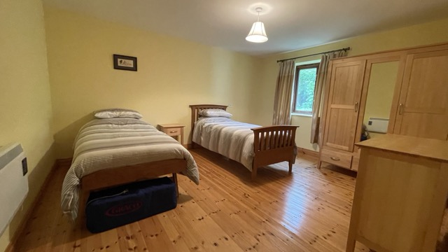 Twin bedroom with wooden floor, wardrobes and window