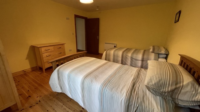 Warm twin bedroom with striped bedding and wooden floor