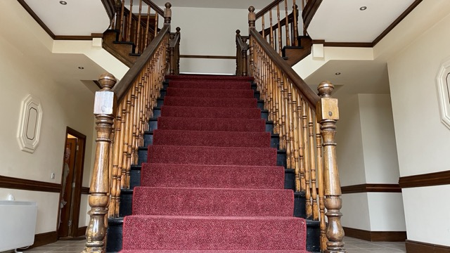 Main entrance staircase with red carpet and timber rails