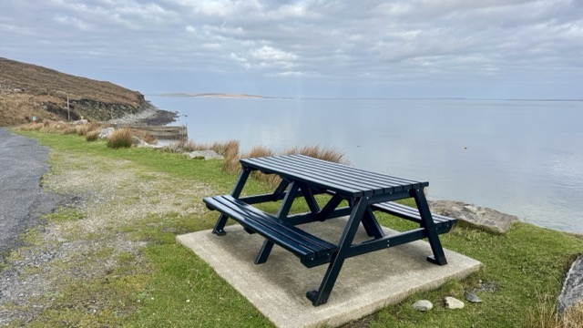 Picnic table overlooking the calm Atlantic water near Dugort